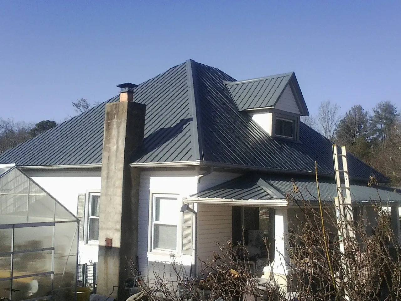 Dark blue standing seam metal roof on a white farmhouse with dormer — Slate & Tile Roof Repair by Roofing Brothers in Munfordville