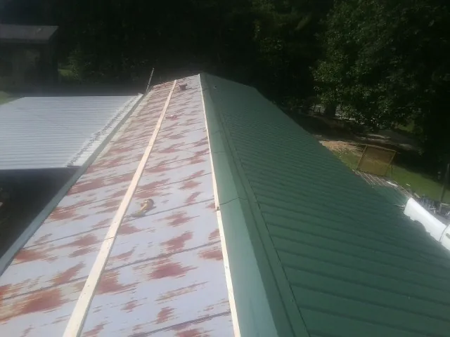 Old rusted panels beside newly installed green metal roofing — Wind Damage Roof Repair by Roofing Brothers in Munfordville