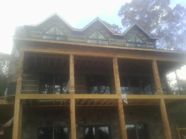 Dormers and porch framing on a large log home under construction — Roof Coating work by our crew in Munfordville
