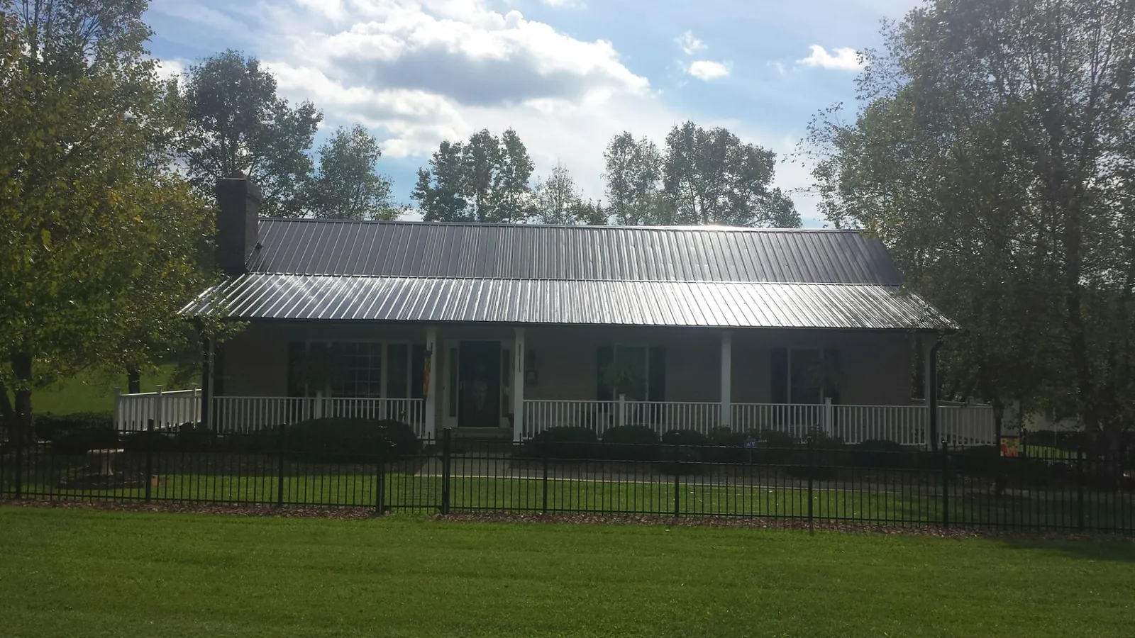 Gray metal roof on a brick ranch with a full width front porch — Gutter Guard Installation work by our crew in Munfordville