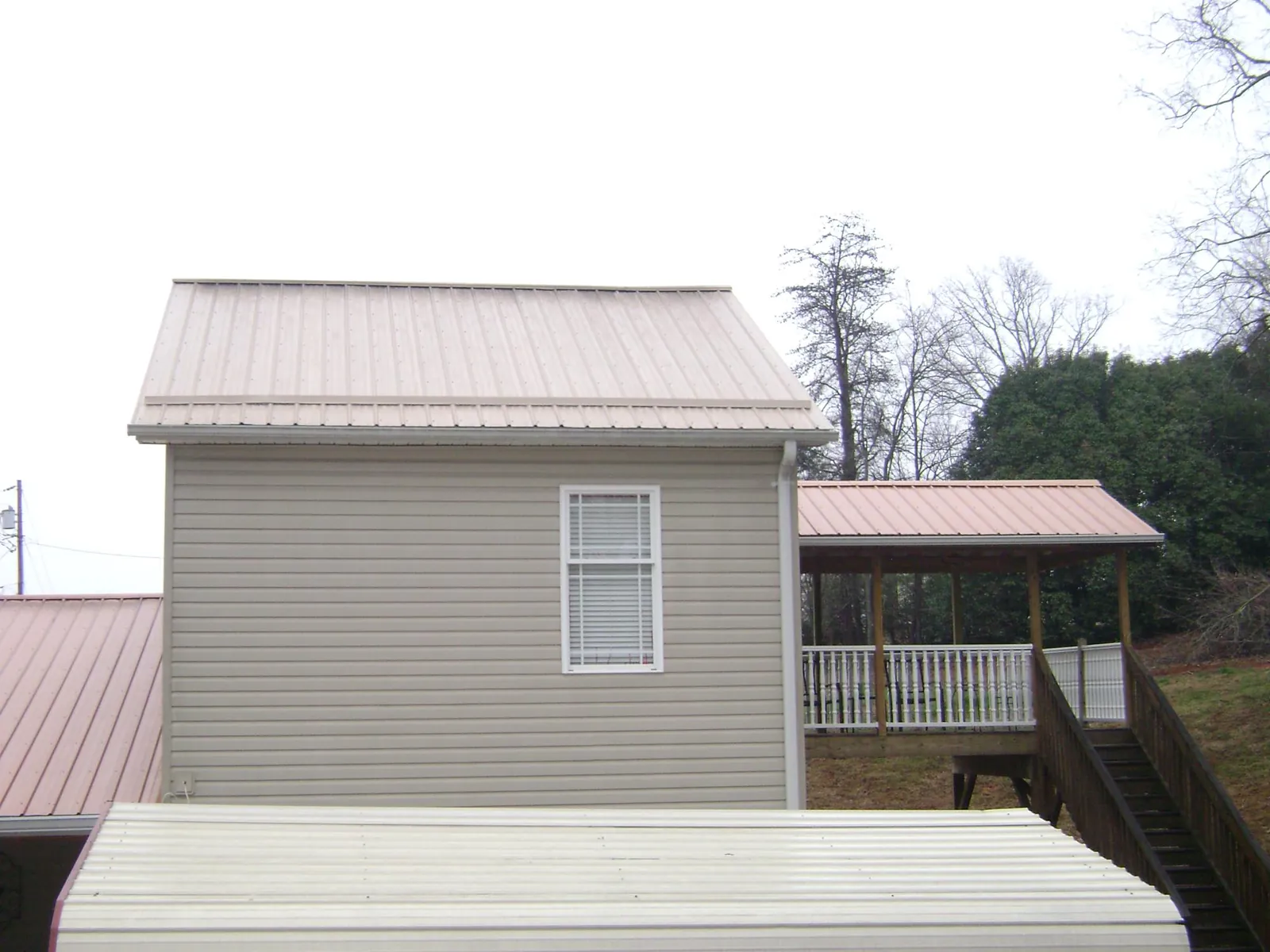 Tan metal roofs on a two story addition and attached porch, from a Roof Replacement job in Munfordville