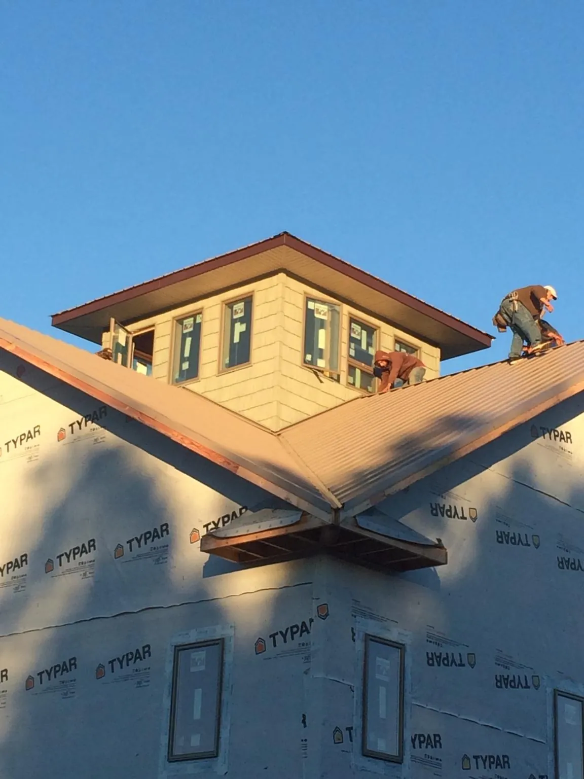Roofers working around a rooftop cupola on a new metal roof at sunset — Roof Waterproofing in Munfordville by Roofing Brothers